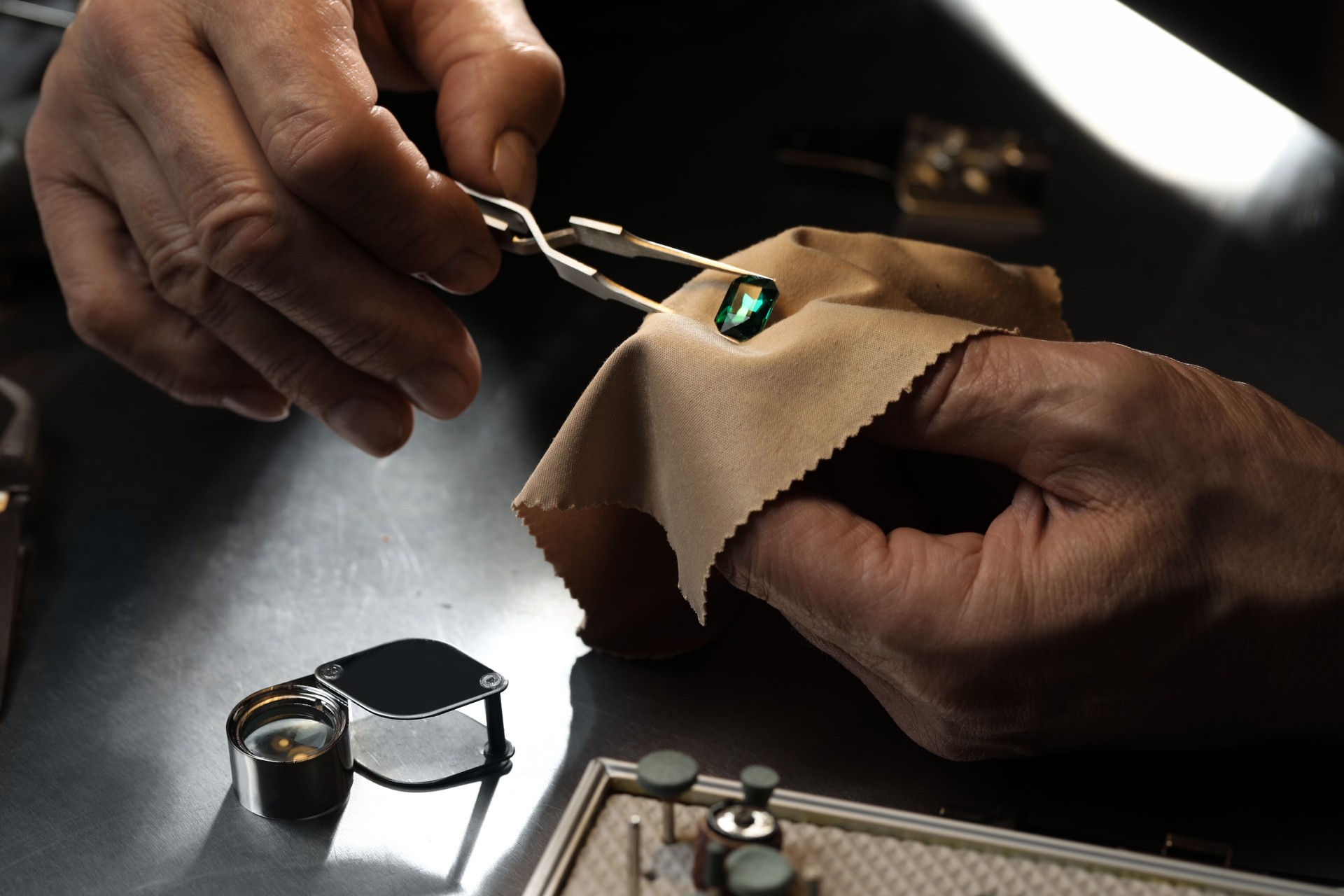 Professional jeweler working with gemstone at table, closeup